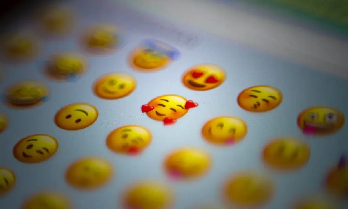 En närbild på en skärm med många gula emoji-ansikten. Ett emoji-ansikte med hjärtögon och ett annat med kyssmun syns tydligt.