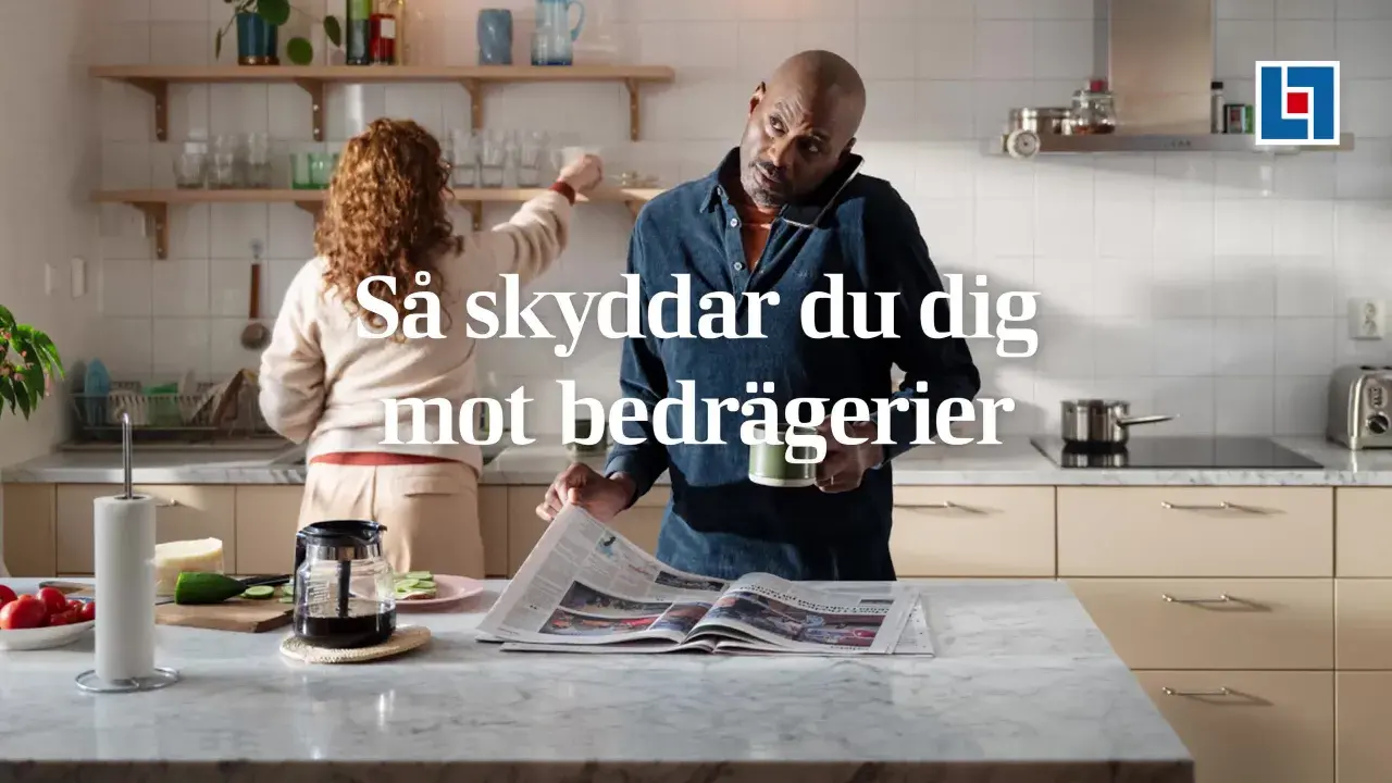 Man i köket pratar i telefon och läser tidningen, medan en kvinna plockar på hyllan. Texten "Så skyddar du dig mot bedrägerier" antyder att "vad betyder cyber" är en viktig fråga för att undvika bedrägerier.