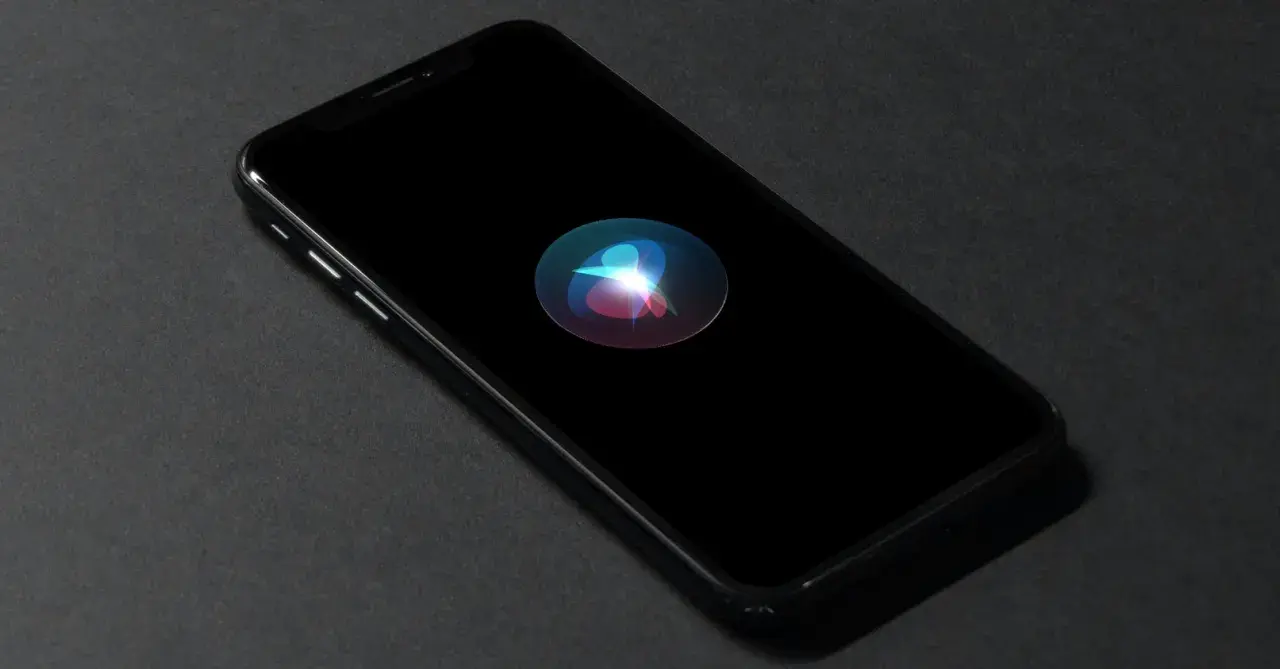 En iPhone med Siri-ikonen lyser på den svarta skärmen. Perfekt för att starta Siri med ett röstkommando.