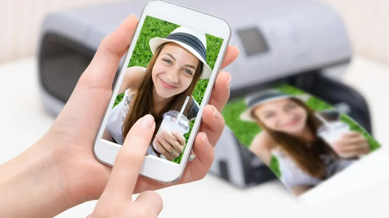 En person håller en mobil med en bild på en leende tjej med hatt. Bredvid syns en utskrift av samma bild från en skrivare. Enkelt att skriva ut från mobilen!
