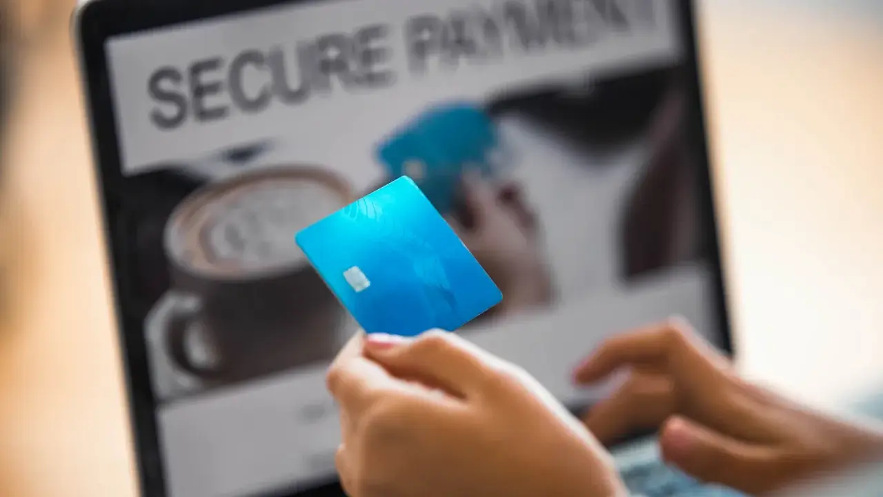 Person håller blått kreditkort framför laptop med texten "SECURE PAYMENT". Tänk om någon har kivra hackat.