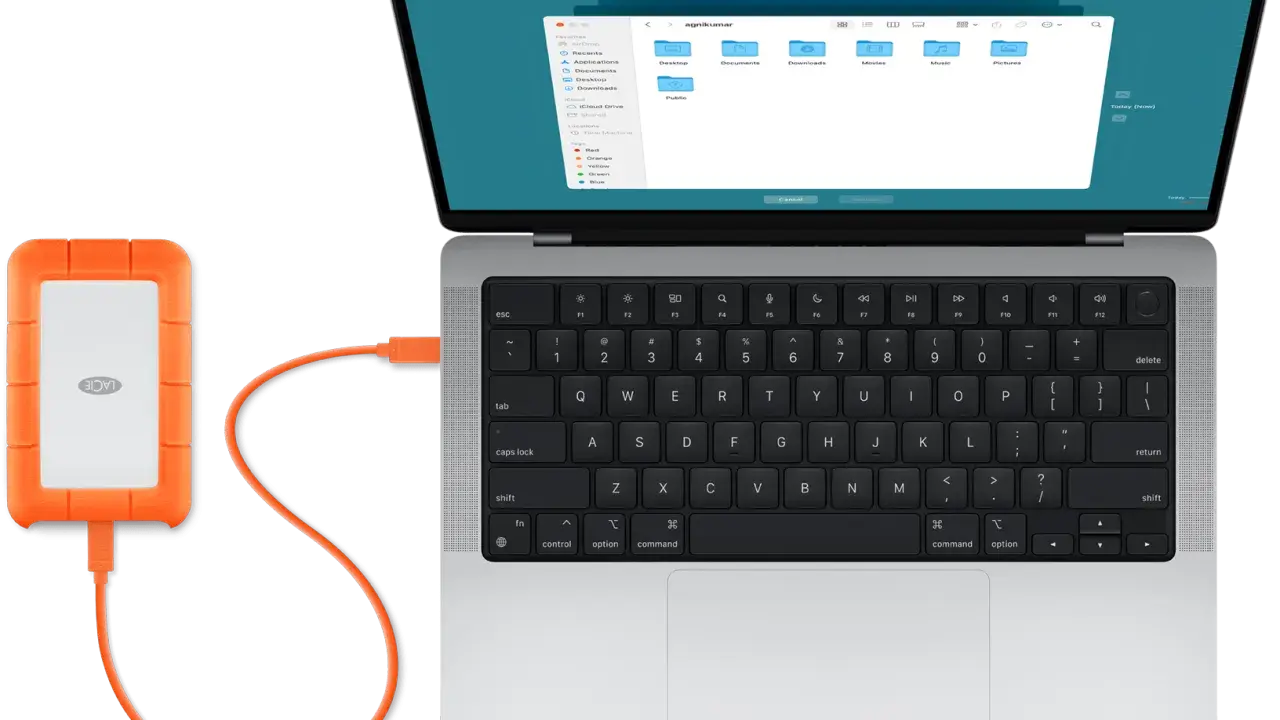 En orange extern hårddisk är ansluten till en MacBook. Perfekt för att backup mac.