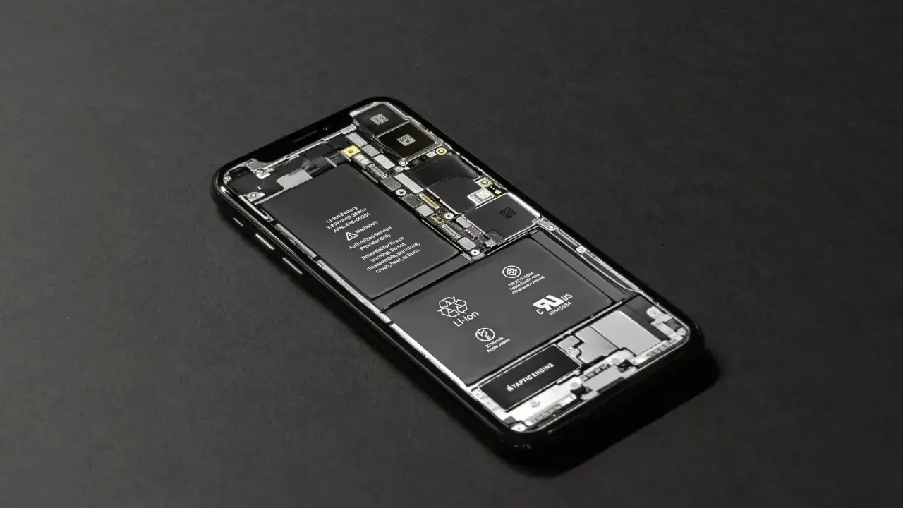 En isärplockad iPhone visar batteri och Taptic Engine. Justering av ljusstyrka iPhone kan påverka batteritiden.