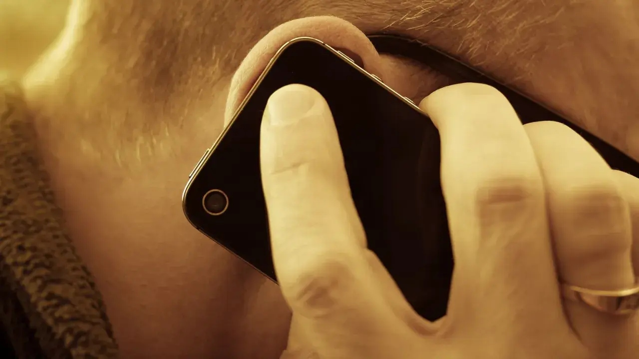 En person lyssnar på sin mobiltelefon. Vem ringde från utlandet 44?