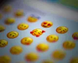 En närbild på en skärm med många gula emoji-ansikten. Ett emoji-ansikte med hjärtögon och ett annat med kyssmun syns tydligt.
