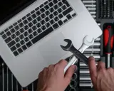 Händer håller skiftnycklar över en laptop, redo att fixa ett Windows 11-problem. Verktygslåda synlig.