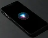 En iPhone med Siri-ikonen lyser på den svarta skärmen. Perfekt för att starta Siri med ett röstkommando.