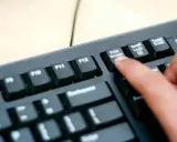 En finger trycker på "Print Screen"-knappen på ett tangentbord. Så här tar man screenshot på datorn.