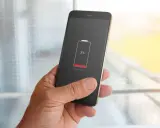 En hand håller en mobil med lågt batteri, 3%. Dags att kolla vilka appar som drar mest batteri.