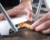 Händer kopplar in en gul nätverkskabel i en vit router, redo att byta router för bättre uppkoppling.