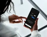 En person håller en mobiltelefon där en chattapp visas. Texten "WELCOME TO CHATS" och "Get started" syns, vilket antyder att man kan skapa grupp sms.