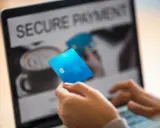 Person håller blått kreditkort framför laptop med texten "SECURE PAYMENT". Tänk om någon har kivra hackat.