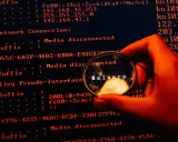 En hand håller ett förstoringsglas över en datorskärm. Förstoringsglaset visar ordet "Malware", vilket indikerar skadlig kod som döljer sig i systemets loggar.