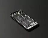 En isärplockad iPhone visar batteri och Taptic Engine. Justering av ljusstyrka iPhone kan påverka batteritiden.