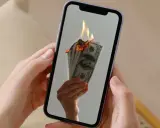 En hand håller en mobil där sedlar brinner. Kanske en bild av en misslyckad apple återbetalning.