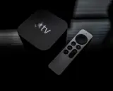Apple TV och fjärrkontroll på mörk bakgrund. Dags att starta om Apple TV för en fräsch start.