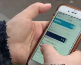En hand håller en mobiltelefon där en person verkar ha råkat teckna en bluff-sms prenumeration.
