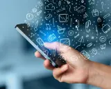 En hand håller en mobil med en mängd ikoner som svävar ut, som ett digitalt måttband i mobilen som mäter allt från väder till kommunikation.