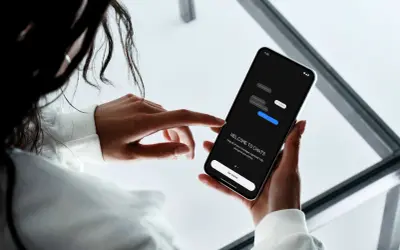 En person håller en mobiltelefon där en chattapp visas. Texten "WELCOME TO CHATS" och "Get started" syns, vilket antyder att man kan skapa grupp sms.