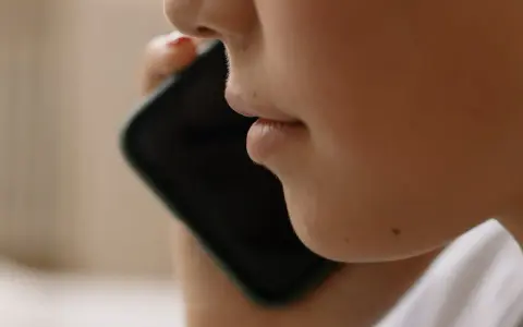 Närbild på en person som pratar i en iPhone. Kanske vill personen spela in telefonsamtal på sin iPhone för att minnas viktiga detaljer.