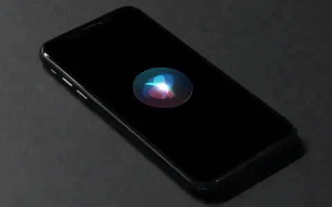 En iPhone med Siri-ikonen lyser på den svarta skärmen. Perfekt för att starta Siri med ett röstkommando.