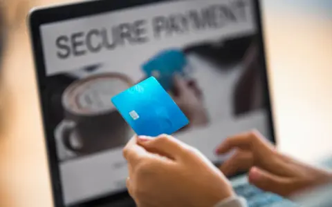Person håller blått kreditkort framför laptop med texten "SECURE PAYMENT". Tänk om någon har kivra hackat.