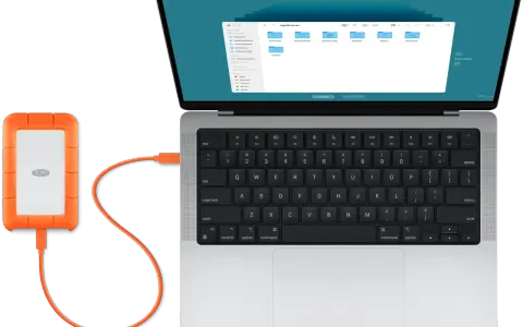 En orange extern hårddisk är ansluten till en MacBook. Perfekt för att backup mac.