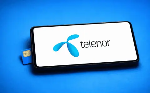 En blå Telenor simkort ligger bredvid en smartphone med Telenors logotyp på skärmen.