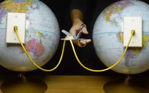 En hand med sax klipper av en gul kabel som kopplar ihop två jordglober. Vem skapade wifi?