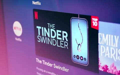 Netflix-skärmen visar "The Tinder Swindler", en dokumentär om tinder bilder på bedragare. En fiskekrok med en diamantring hänger i en mobil.