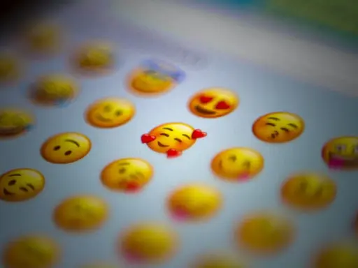 En närbild på en skärm med många gula emoji-ansikten. Ett emoji-ansikte med hjärtögon och ett annat med kyssmun syns tydligt.