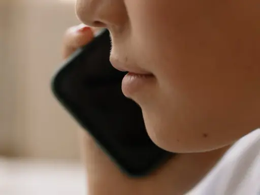 Närbild på en person som pratar i en iPhone. Kanske vill personen spela in telefonsamtal på sin iPhone för att minnas viktiga detaljer.