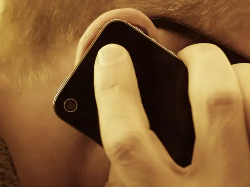 En person lyssnar på sin mobiltelefon. Vem ringde från utlandet 44?