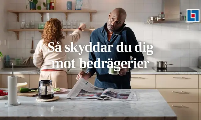 Man i köket pratar i telefon och läser tidningen, medan en kvinna plockar på hyllan. Texten "Så skyddar du dig mot bedrägerier" antyder att "vad betyder cyber" är en viktig fråga för att undvika bedrägerier.