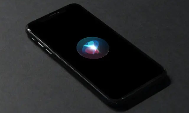En iPhone med Siri-ikonen lyser på den svarta skärmen. Perfekt för att starta Siri med ett röstkommando.