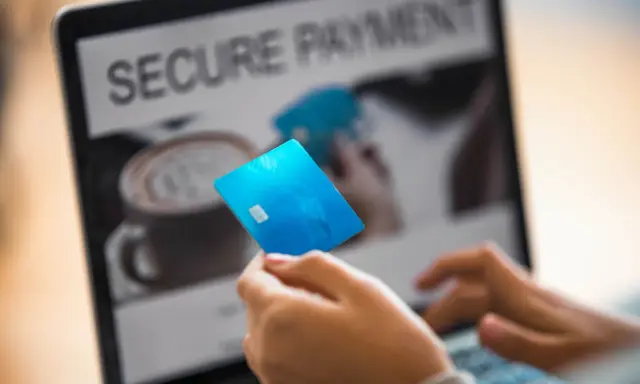 Person håller blått kreditkort framför laptop med texten "SECURE PAYMENT". Tänk om någon har kivra hackat.