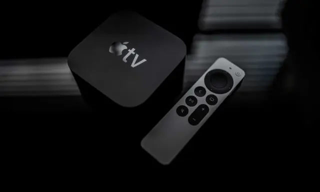 Apple TV och fjärrkontroll på mörk bakgrund. Dags att starta om Apple TV för en fräsch start.