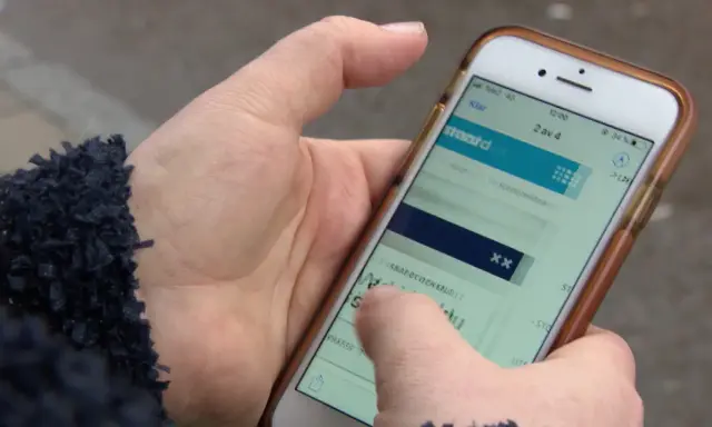 En hand håller en mobiltelefon där en person verkar ha råkat teckna en bluff-sms prenumeration.