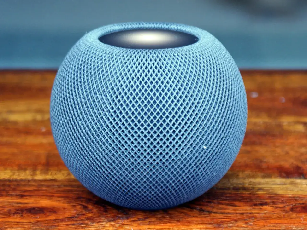 En blå Apple HomePod mini på ett träbord. En perfekt liten högtalare för ett hem.