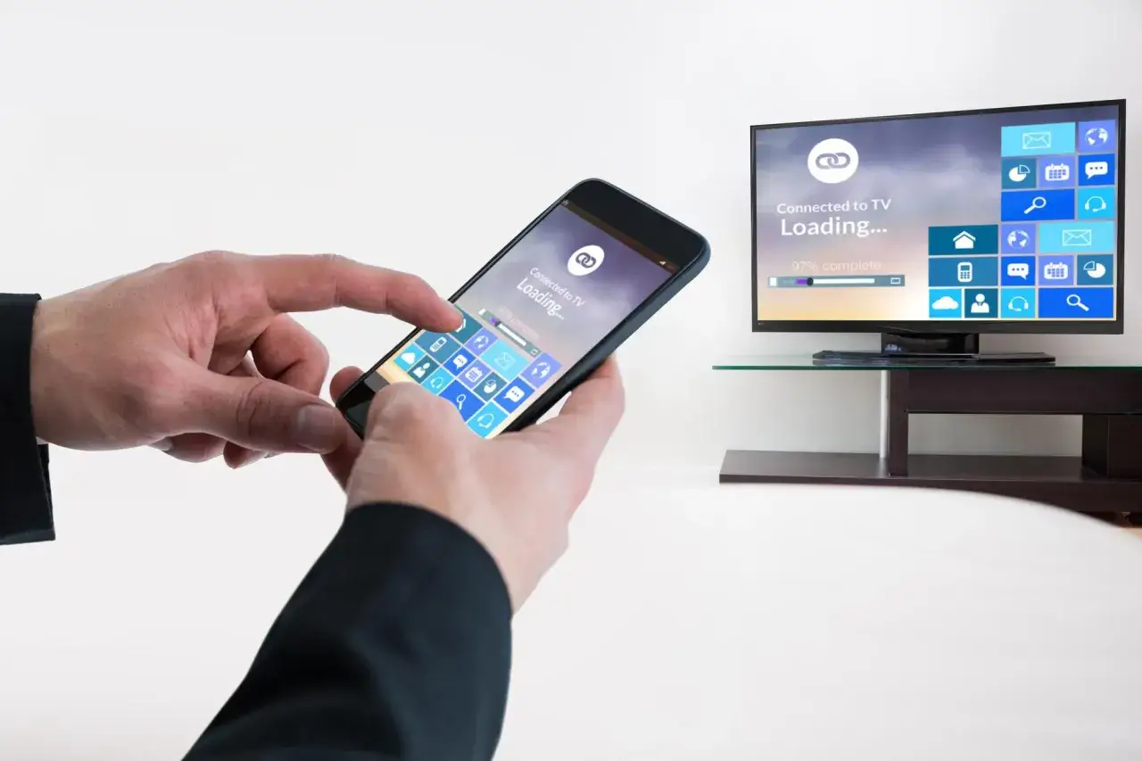H&auml;nder som styr en mobil f&ouml;r att visa bilder p&aring; tv. Sk&auml;rmen visar 