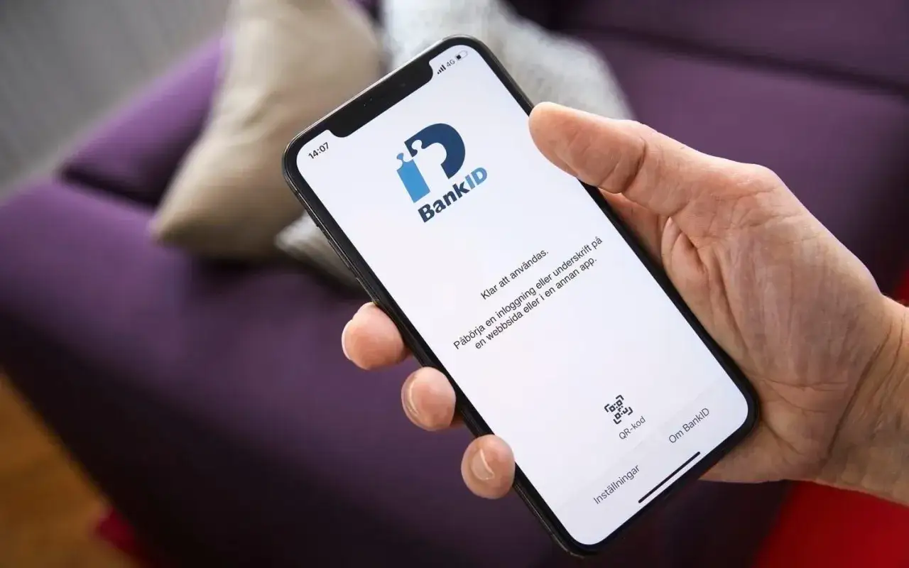 En hand håller en mobil med BankID-appen öppen. Var försiktig med misstänkta SMS som kan leda till phishing.