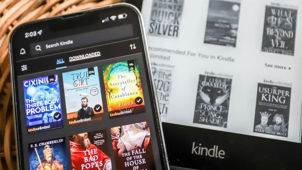 En smartphone visar b&ouml;cker fr&aring;n Kindle Unlimited Sverige. En e-l&auml;sare i bakgrunden visar ocks&aring; titlar.