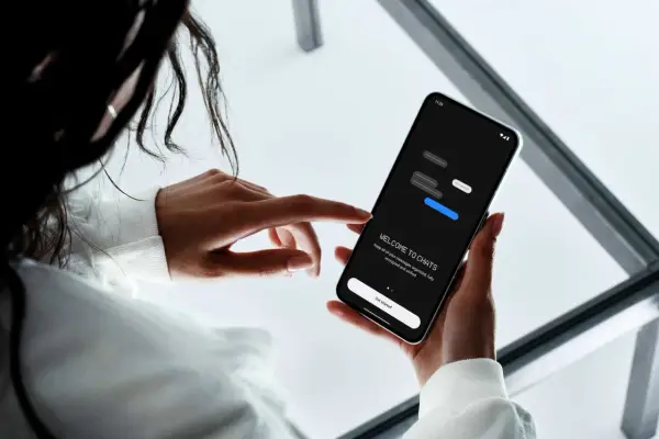 En person håller en mobiltelefon där en chattapp visas. Texten "WELCOME TO CHATS" och "Get started" syns, vilket antyder att man kan skapa grupp sms.